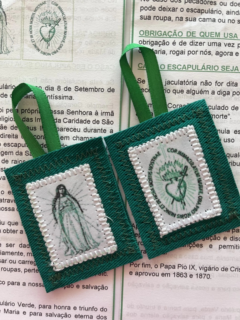 Detalhe do escapulário verde aberto sobre folheto antigo de devoção